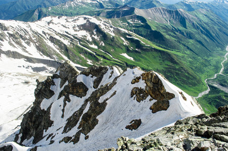 Mountain landscape with steep alpine peaks on the foreground and more sloping textured mountains on the backgroundの写真素材