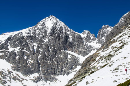 Climber approaching the climbing route. In the background is steep alpine peak with the observatory atop of itの写真素材