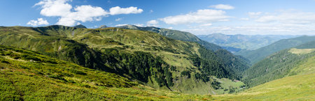 Panoramic view of mountain ridges with a village in the background in sunny summer dayの写真素材