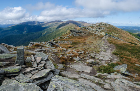 Hiker walks the stony road on the mountain ridge with a former Polish-Czechoslovak border column in the foregroundの写真素材