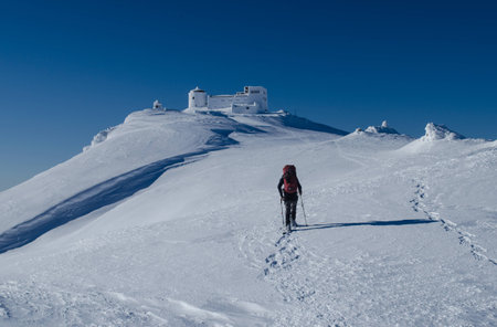 Winter picture of a hiker walking towards the abandoned observatory atop the mountain Pip Ivan in Ukrainian Carpathiansの写真素材