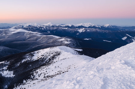 View of snow-capped mountains topped with colorful sunrise skyの写真素材