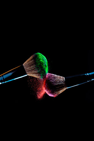 Makeup brush with red and green powder explosion isolated on black backgroundの写真素材