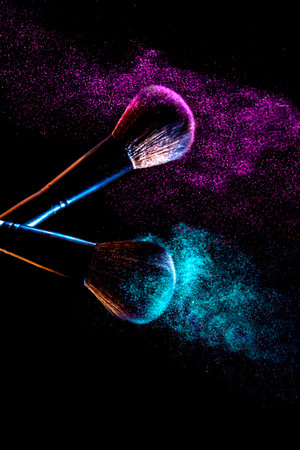 Makeup brushes with colorful powder explosion on black background. abstract backgroundの写真素材