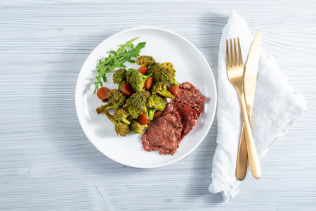 Breakfast in a white plate of broccoli vegetables, herbs and ham slicesの写真素材