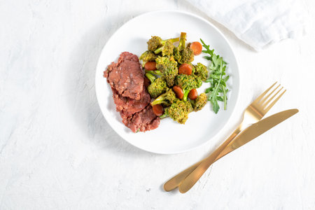 Roast beef with broccoli and arugula salad on white plateの写真素材