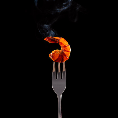 Shrimps on a fork with smoke on a black background.の写真素材