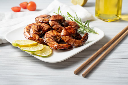 Grilled tiger prawns with lemon and rosemary on white plateの写真素材