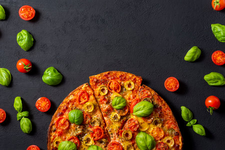 Pizza with tomatoes, olives and basil on a black backgroundの写真素材