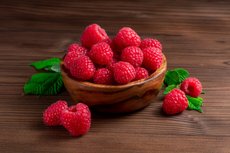 Ripe raspberries in a wooden bowl on a wooden backgroundの写真素材