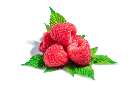 Fresh raspberries with green leaves isolated on a white background.