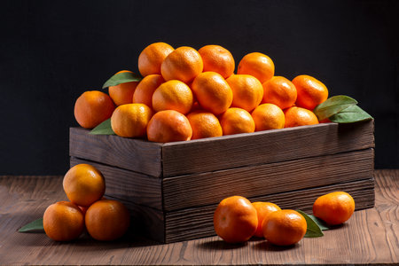 Group of tangerines in a wooden box on a dark backgroundの写真素材