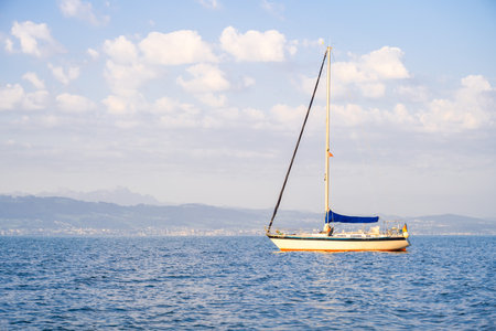 Sailboat in the sea on a background of mountains and blue sky