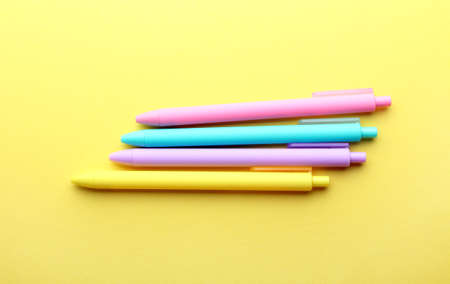 Yellow,purple,blue and pink pens on yellow background. Top view, flat lay.の写真素材