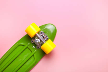 Close up of green skateboard with yellow wheels on pink background. Plastic mini cruiser board. Creative concept. Minimalism, flat lay, copy spaceの写真素材