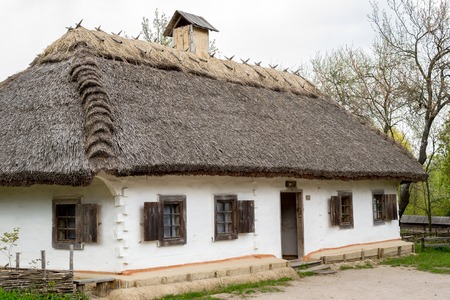 National Museum Pirogovo in the outdoors near Kiev. Ancient peasant Ukrainian house in the spring with a thatched roof in the old village of national architecture, Ukraine.のeditorial素材