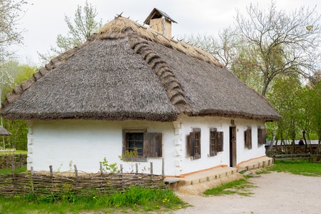 National Museum Pirogovo in the outdoors near Kiev. Ancient peasant Ukrainian house in the spring with a thatched roof in the old village of national architecture, Ukraine.のeditorial素材