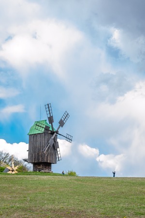 National Museum Pirogovo in the outdoors near Kiev. Ukraine - April 23, 2017: Ancient traditional wooden windmill, beautiful spring landscape with sky. National architecture.のeditorial素材