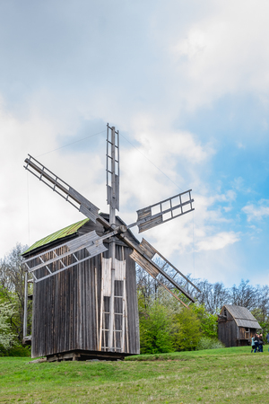 National Museum Pirogovo in the outdoors near Kiev. Ukraine - April 23, 2017: Ancient traditional wooden windmill, beautiful spring landscape with sky. National architecture.のeditorial素材