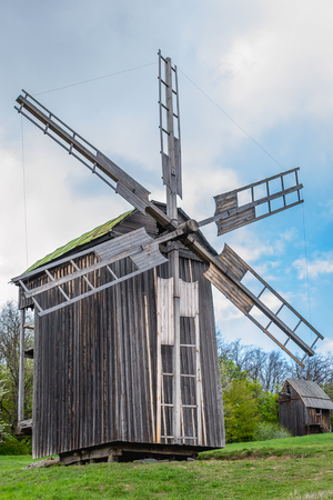 National Museum Pirogovo in the outdoors near Kiev. Ancient traditional wooden windmill, beautiful spring landscape with sky. National architecture.のeditorial素材