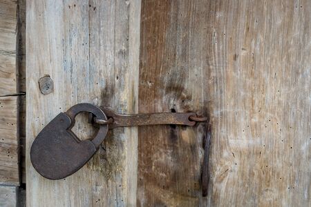 Natural material. Old metal rusty padlock, bolt on a wooden door. Old wooden brown background close-up.の写真素材