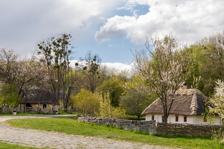 National Museum Pirogovo in the outdoors near Kiev. Ancient peasant Ukrainian house with a thatched roof, spring landscape in the old village of national architecture, Ukraine.のeditorial素材