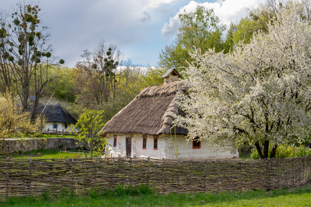 National Museum Pirogovo in the outdoors near Kiev. Ancient peasant Ukrainian house with a thatched roof, spring landscape in the old village of national architecture, Ukraine.のeditorial素材