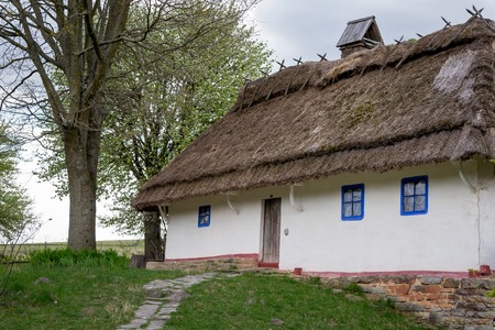 National Museum Pirogovo in the outdoors near Kiev. Ancient peasant Ukrainian house with a thatched roof, spring landscape in the old village of national architecture, Ukraine.のeditorial素材
