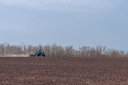 An old tractor in the field plows the land. Spring landscape of a countryside, a farm.の写真素材