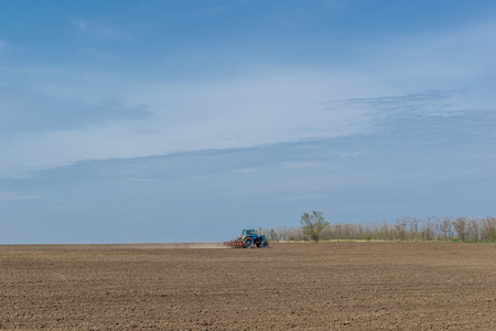 An old tractor in the field plows the land. Spring landscape of a countryside, a farm.の写真素材