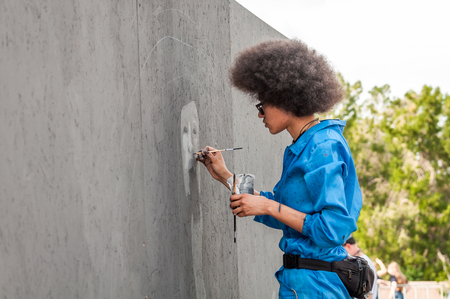Ukraine, Nikolaev, 24.06.17: Festival of graffiti dedicated to the Day of Youth. The central square of the city. Young beautiful African-American girl Sandra Sambo draws graffiti.のeditorial素材