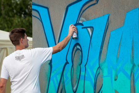 Ukraine, Nikolaev, 24.06.2017: Festival of graffiti dedicated to the Day of Youth. The central square of the city. Young boy drawing graffiti on a wall with a spray.のeditorial素材