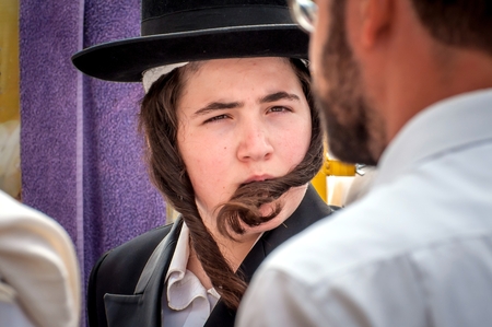 A young Hasid in a traditional Jewish hat and with long payos. Uman, Ukraine - 21 September 2017: Rosh Hashanah, Jewish New Year.のeditorial素材