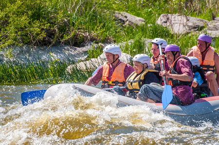 Myhiya, Ukraine - May 1, 2018: Rafting. Cheerful group of people aged are sailing on a rubber inflatable boat. Teamwork. Extreme sport. Ecological water tourism. Positive emotions, adrenalineのeditorial素材