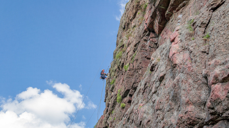 Yuzhnoukrainsk, Ukraine - June 19, 2018: Rock climbing. A young climber climbs a vertical granite rock. Extreme sport. Training of mountaineersのeditorial素材
