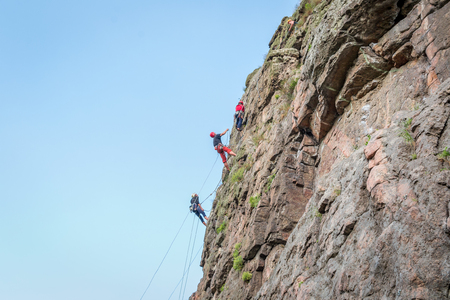 Rock climbing. A group of young rock climbers climb the vertical granite rock. Extreme sportの写真素材