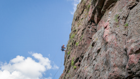 Yuzhnoukrainsk, Ukraine - June 19, 2018: Rock climbing. A young climber climbs a vertical granite rock. Extreme sport. Training of mountaineersのeditorial素材
