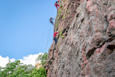 Yuzhnoukrainsk, Ukraine - June 19, 2018: Rock climbing. A group of young rock climbers climb the vertical granite rock. Extreme sport. Training of mountaineersのeditorial素材