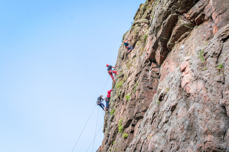 Yuzhnoukrainsk, Ukraine - June 19, 2018: Rock climbing. A group of young rock climbers climb the vertical granite rock. Extreme sport. Training of mountaineersのeditorial素材