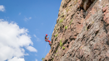 Yuzhnoukrainsk, Ukraine - June 19, 2018: Rock climbing. A young climber climbs a vertical granite rock. Extreme sport. Training of mountaineersのeditorial素材