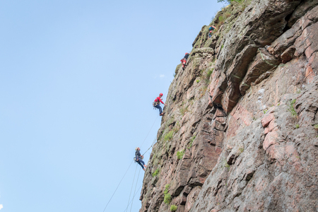 Yuzhnoukrainsk, Ukraine - June 19, 2018: Rock climbing. A group of young rock climbers climb the vertical granite rock. Extreme sport. Training of mountaineersのeditorial素材