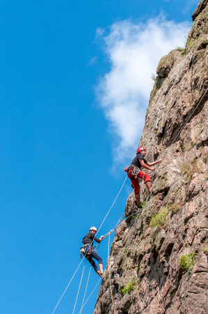 Yuzhnoukrainsk, Ukraine - June 19, 2018: Rock climbing. A group of young rock climbers climb the vertical granite rock. Extreme sport. Training of mountaineers.のeditorial素材