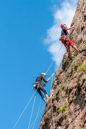 Yuzhnoukrainsk, Ukraine - June 19, 2018: Rock climbing. A group of young rock climbers climb the vertical granite rock. Extreme sport. Training of mountaineers.のeditorial素材
