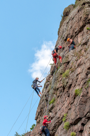 Yuzhnoukrainsk, Ukraine - June 19, 2018: Rock climbing. A group of young rock climbers climb the vertical granite rock. Extreme sport. Training of mountaineers.のeditorial素材