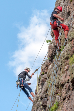 Yuzhnoukrainsk, Ukraine - June 19, 2018: Rock climbing. A group of young rock climbers climb the vertical granite rock. Extreme sport. Training of mountaineers.のeditorial素材