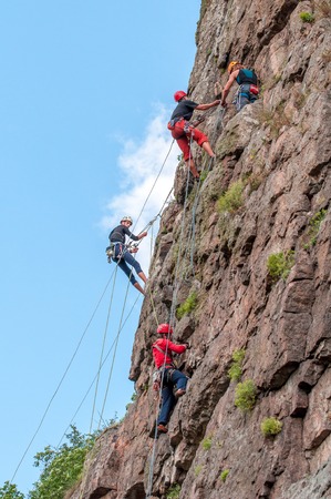 Yuzhnoukrainsk, Ukraine - June 19, 2018: Rock climbing. A group of young rock climbers climb the vertical granite rock. Extreme sport. Training of mountaineers.のeditorial素材