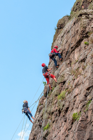 Yuzhnoukrainsk, Ukraine - June 19, 2018: Rock climbing. A group of young rock climbers climb the vertical granite rock. Extreme sport. Training of mountaineers.のeditorial素材