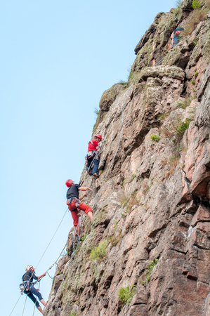 Yuzhnoukrainsk, Ukraine - June 19, 2018: Rock climbing. A group of young rock climbers climb the vertical granite rock. Extreme sport. Training of mountaineers.のeditorial素材