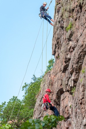 Yuzhnoukrainsk, Ukraine - June 19, 2018: Rock climbing. A group of young rock climbers climb the vertical granite rock. Extreme sport. Training of mountaineers.のeditorial素材