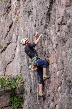 Yuzhnoukrainsk, Ukraine - June 19, 2018: Rock climbing. A young climber climbs a vertical granite rock. Extreme sport. Training of mountaineers.のeditorial素材